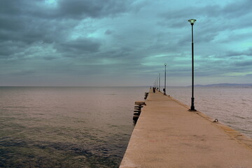 Weit ins Meer reichender Bootssteg vor dramatischem Himmel