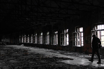 Dark corridor of abandoned building with row of windows and walking man