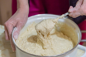 Cooking dough for pies. The girl kneads flour and makes dough.