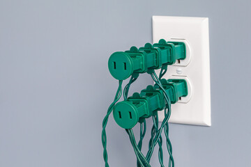 Electrical outlet overloaded with Christmas string lights. Holiday decoration safety, hazards and...