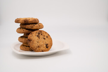 Close-up of a gingerbread cookie with chocolate leans on a stack on a white plate isolated on a white background.