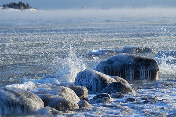 Ice covered rock by the Baltic Sea that about to freeze over with water splashing against the rocks in Helsinki, Finland on 14 January 2021.