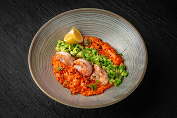 Delicate risotto with shrimps and avocado in a ceramic plate on a dark textured background. Restaurant menu Isolated on black
