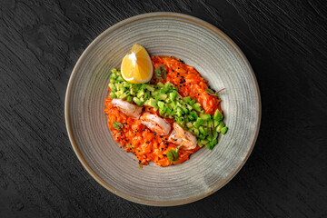 Delicate risotto with shrimps and avocado in a ceramic plate on a dark textured background. Restaurant menu Isolated on black