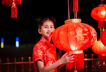 Cute little girl in red chinese dress holding lanterns on chinese new year