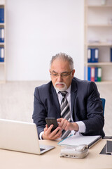 Naklejka premium Old male employee working in the office
