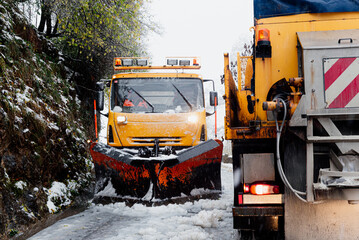 two snow plows cross on a narrow snowy road while working.