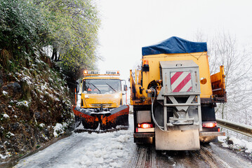 two snow plows cross on a narrow snowy road while working.