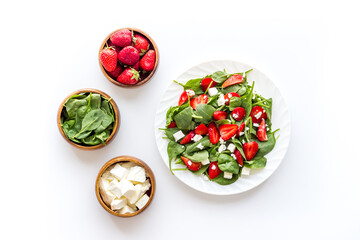 Green spinach salad with red strawberry and goat cheese, top view