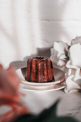 Caneles de bordeaux with rose under sunlight. French pastry Canele rum and vanilla flavor thick caramelized crust
