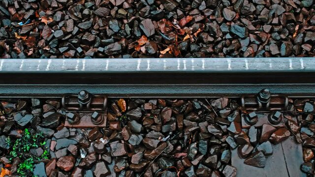 Wet Iron Railway Train Tram Track Rails With Rocky Ballast Bolts and Sleepers on Autumn Rainy Day