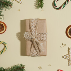 Christmas present wrapped in kraft paper. Top view. Gift box and Christmas decoration on beige background.