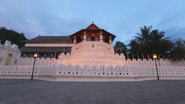 Static view of the beautiful Temple of the Sacred Tooth Relic or Sri Dalada Maligawa with white walls and red roof at sunset in Sri Lanka, Dec. 2014