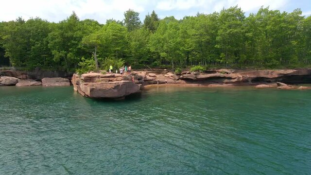 People cliff jumping from a rock into Lake Superior on a summer day, having fun at Madeline island Apostle island Lake Superior Wisconsin, travel and enjoy the outdoors