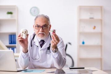 Old male doctor demonstrating human skull