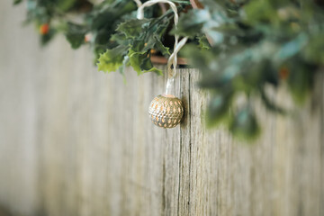 Mistletoe and delicate Christmas lights strewn along rustic wooden seat with copy space. Golden bokeh in background.