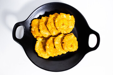 fried patacones on black plate with white background