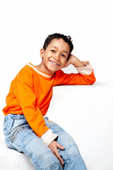 Funny mixed race kid boy in orange sweater posing on white background