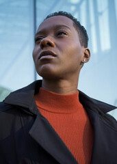 Portrait of a young woman in a black coat and orange mock turtleneck shirt