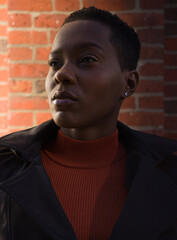 Portrait of a young woman in a black coat and orange mock turtleneck shirt