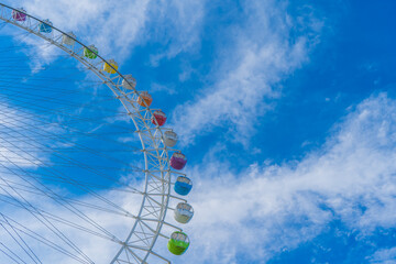 遊園地の巨大な観覧車と、鮮やかな青空と雲