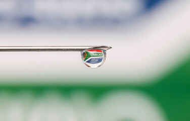 Close up shot of syringe with droplet , see through of South Africa flag with new COVID variant, Omicron text on it.