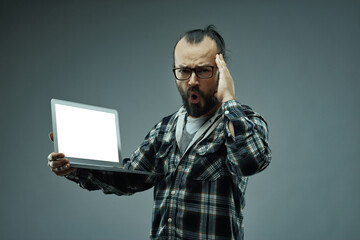 Man with an amazed facial expression while holding a laptop