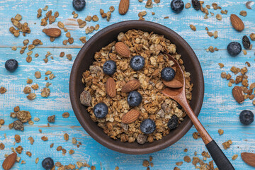 A large bowl overflowing with muesli with berries and nuts on a rustic table. Flat lay.