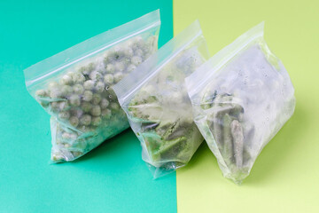Frozen vegetables in plastic bags, zip bags with fastener on a green background close-up.