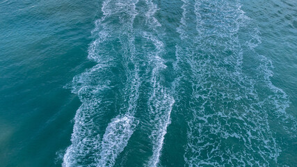 Aerial bird eyes view of jet ski boat cruising in high speed in turquoise clear water sea.