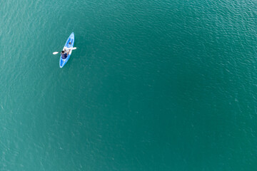 Unidentified man on sea Kayaker Aerial View during sunset. Caucasian Sportsman in the Yellow and Blue Kayak Paddling on the Scenic sea Along the Shore. © chayakorn
