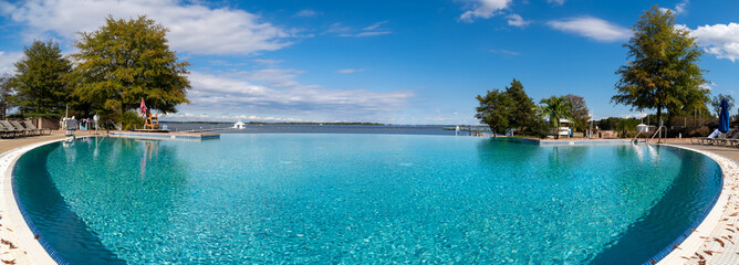 panoramic view of an infinity swimming pool in a resort with blue water and palm tree perfect for vacation