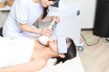 サロンの機械で脱毛の施術をするスタッフと女性のお客