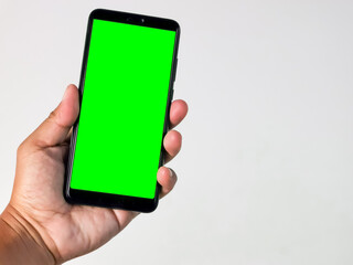 Hand holding smartphone with green screen isolated on white background.