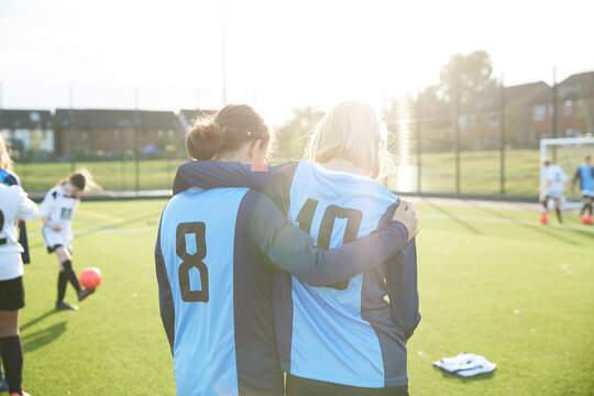 UK, Rear view of female soccer team members (10-11, 12-13) embracing in field