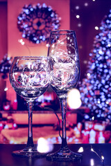 A champagne glass and a wine glass, shining with hundreds of lights. The glow of the light bulbs in the glasses brings a festive mood and charges with positivity.