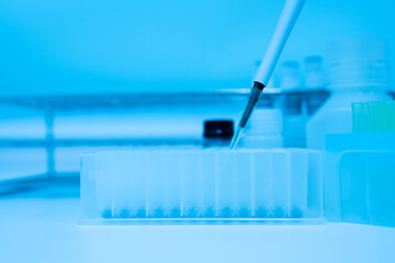 Selective focus pipette putting sample in the plate for taking immunochemistry  and reagent bottle on white table background for laboratory analysis..Conceptual image COVID-19 test tube sample.