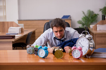 Young male employee sleeping in the office in time management co