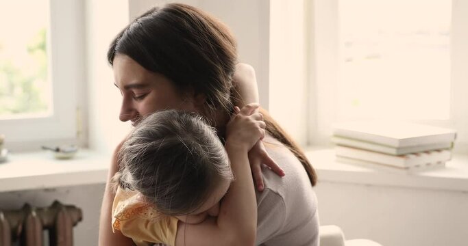 Tender young mom small preschool age daughter meeting after being apart long time missing one another cuddling kissing hugging enjoy reunification. Happy mum embrace child girl reconciling after fight