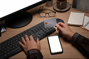 Young man holding credit card and having payment online or shopping online with computer.