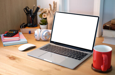 Mock up computer laptop with blank display, red coffee cup and books on wooden table.