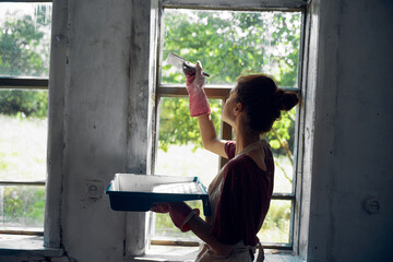 woman paints windows in the house interior room renovation