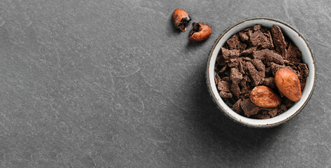 Cacao beans on grey concrete background. Raw fermented. organic cocoa seeds for hot chocolate drink. Flat lay, copy space for food and drink recipe. Healthy nibs