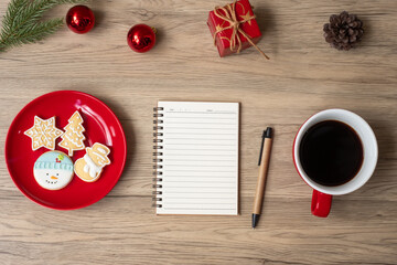 Blank notebook, black coffee cup, Christmas cookies and pen on wood table, Top view and copy space. Xmas, Happy New Year, Goals, Resolution, To do list, Strategy and Plan concept