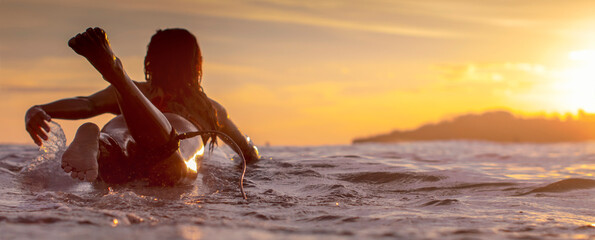 Landscape image of Sunset scene with a girl on a surfboard