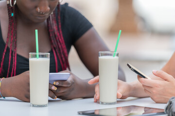 Close-up view of two glasses of milkshakes on the table being drunk by two friends in the open air