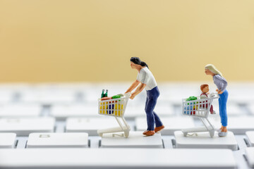 Miniature shoppers push a trolley on a keyboard. Concept of decreasing in foot traffic after the...