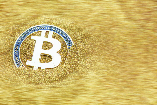 Bitcoin / cryptocurrency or digital token concept : Golden coin and B symbol with 0, 1 digital code, appear on gold glitter sand, depicts the investing in new emerged virtual money / intangible asset
