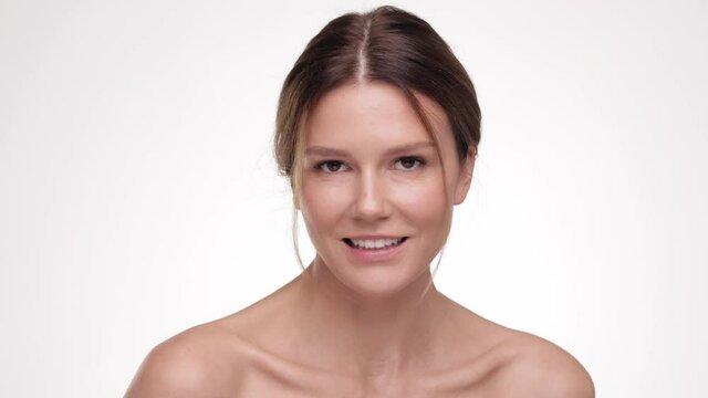 Close up portrait beautiful brunette hair woman. Beauty and skin care. Adorable young half-naked female look at the camera and smiling. Advertising fresh clean healthy skin care concept. Slow motion.