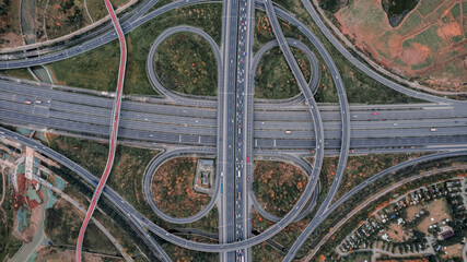 Top down aerial view from drone on modern traffic junction of multiple lane highway road in metropolis city. Heavy traffic on motorways. Elevated curved roads, clover shape bridge with no speed limit.